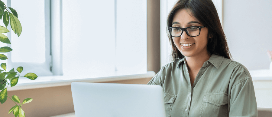 Young woman in glasses smiling at laptop
