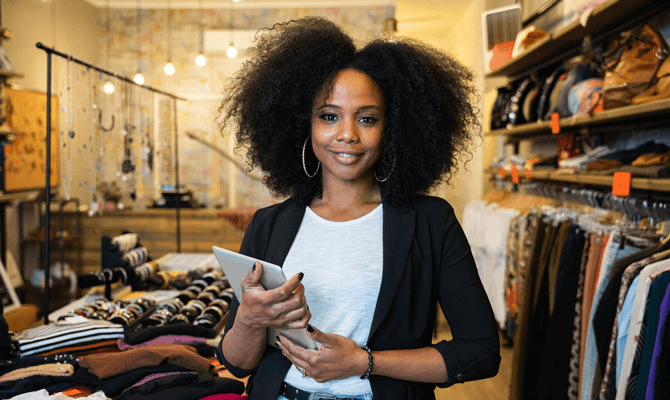Confident woman holding tablet in clothing store