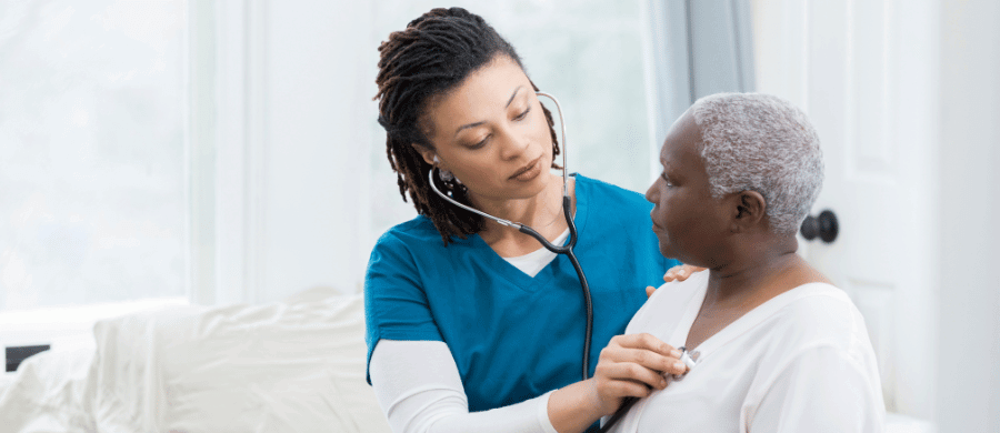 Nurse using stethoscope on older woman