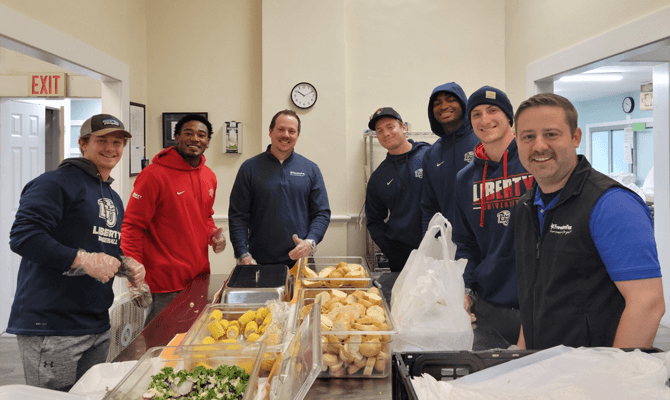 Freedom First employees and Liberty University athletes volunteering in a community kitchen