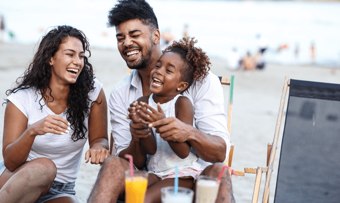 Young parents laughing with daughter on the beach